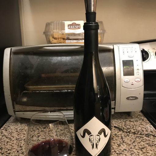 Photo of a Riedel Pinot Noir wine glass with a bottle of 2015 Battle Creek Vineyard Pinot Noir.