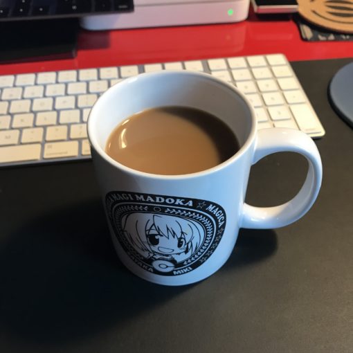 Photo of a white coffee mug on a black mat on a red desk.