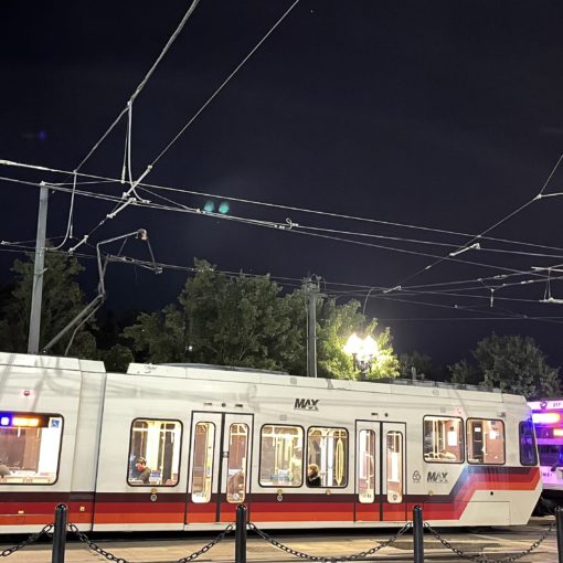 Photo of TriMet MAX car 216 at Rose Quarter with a failed pantograph caught in the overhead wire. Part of the wire can be seen lying on the rear roof of the car.