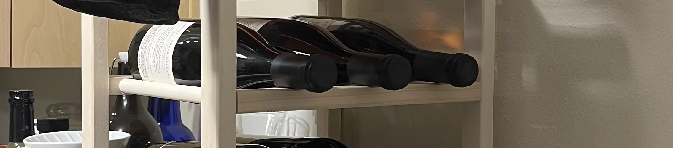Photo of three wine racks from IKEA stacked on top of eachother filled with several bottles of wine.