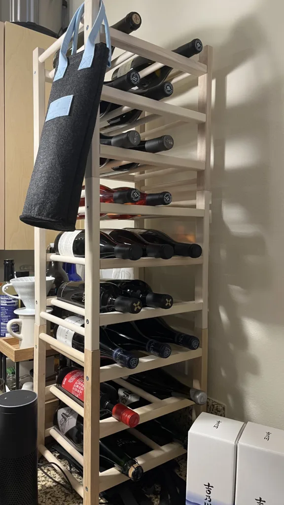 Photo of three wine racks from IKEA stacked on top of eachother filled with several bottles of wine.
