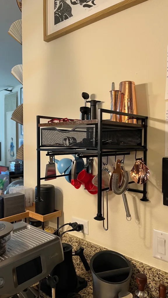 Photo of a kitchen organizer hung on the wall above an espresso machine.